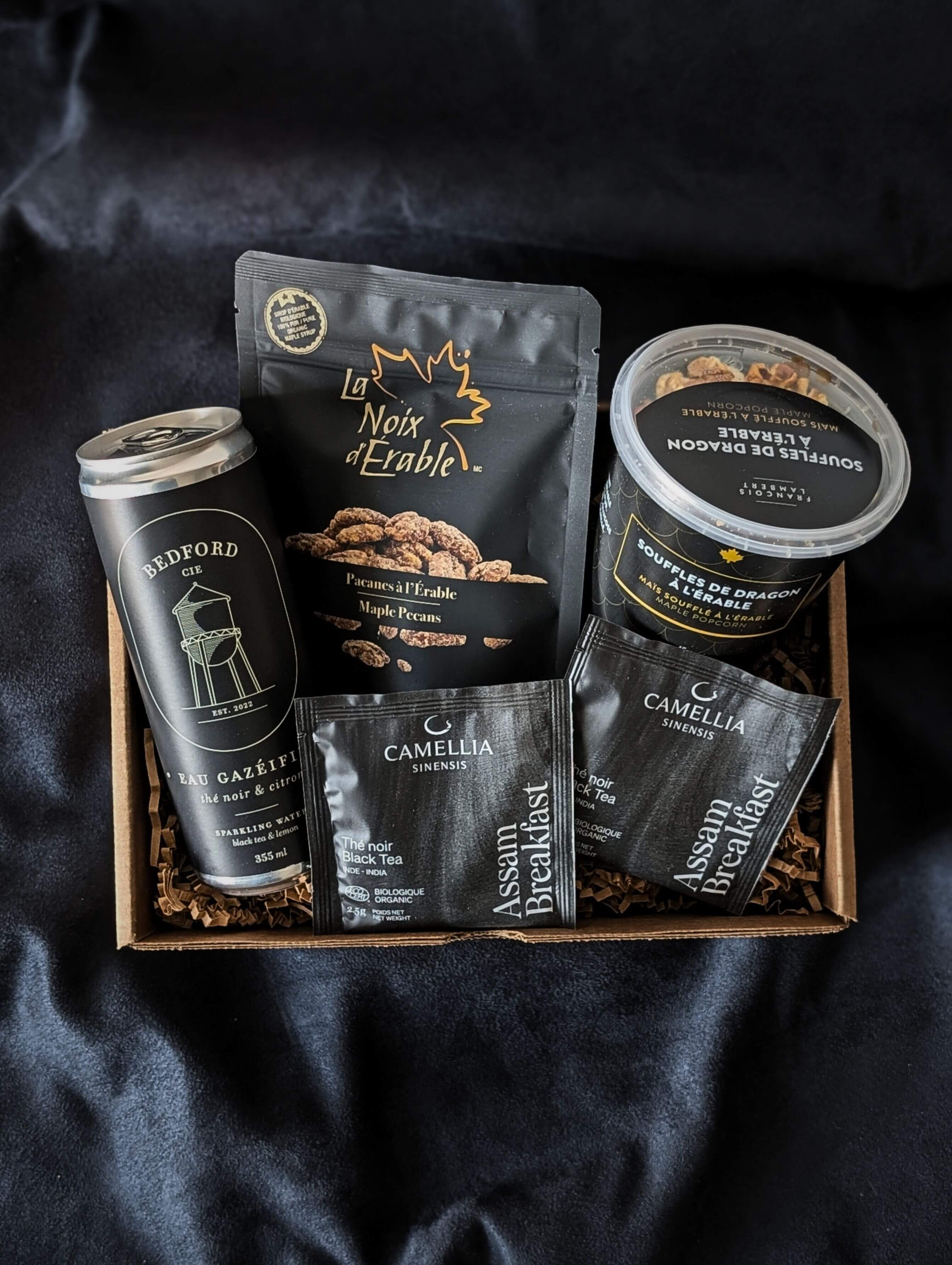 Boîte cadeau corporative gourmande Noir avec pacanes à l’érable, soufflés sucrés et eau pétillante thé noir citron